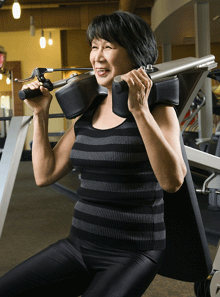 Mature woman using strength training machine